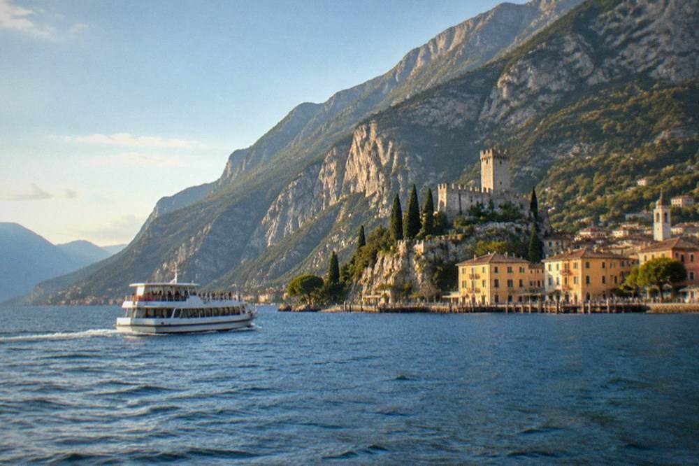 A ferry crossing open water with a mountain ridge rising behind a northern lakeside village