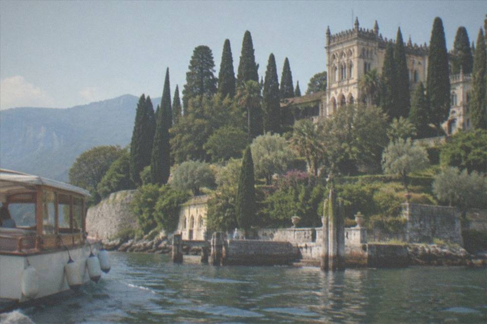 A small boat approaching the island's jetty with the villa and terraced gardens rising behind