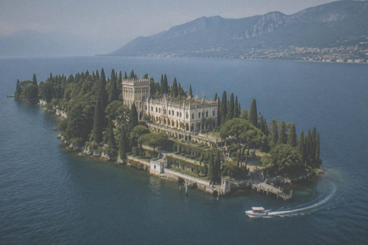 Aerial view of Isola del Garda with its villa and gardens surrounded by blue lake water