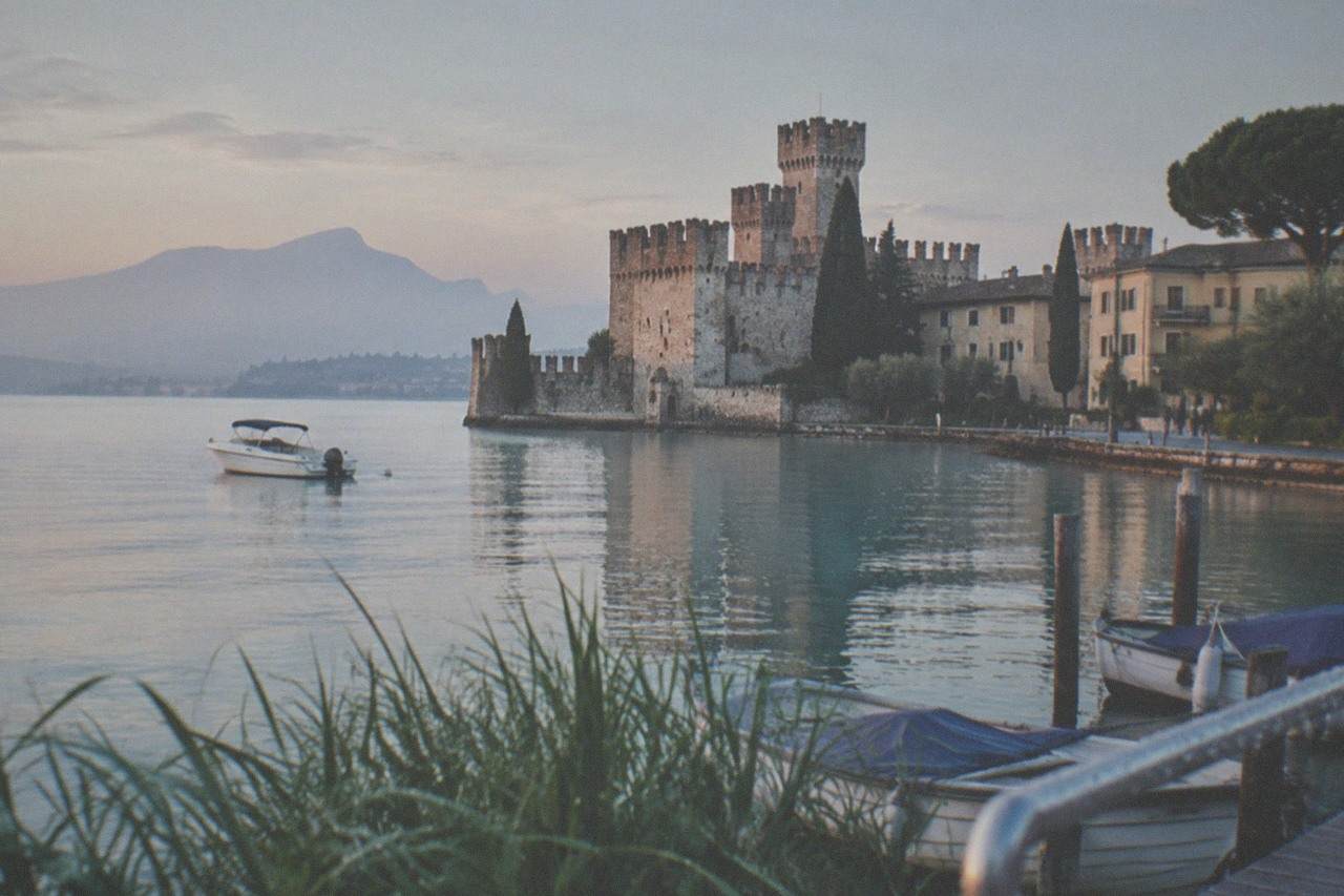 A calm morning on Lake Garda with a small boat near the Sirmione peninsula shoreline