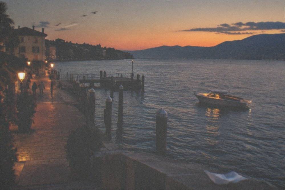 An open private motorboat at dusk on Lake Garda with warm light on the water and hills in the distance