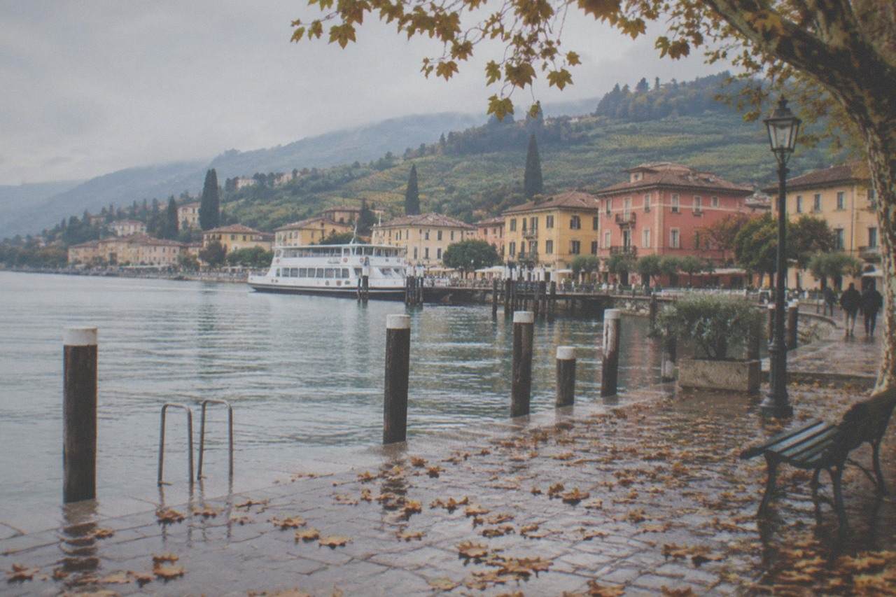 A lakeside town on Lake Garda with pastel buildings and mountains rising behind the water