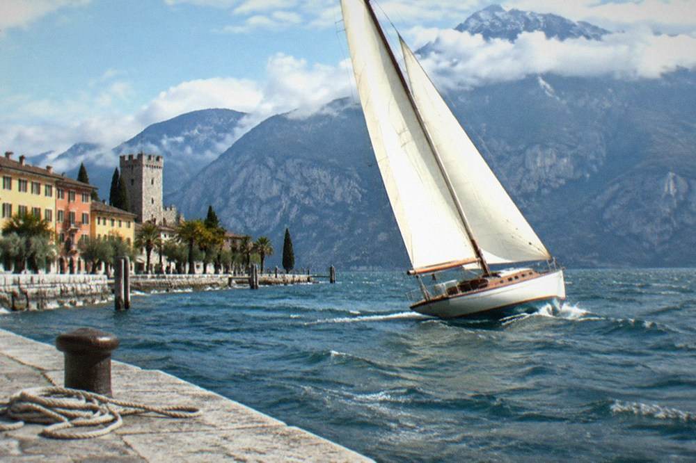 Historic sailboat with full sails on open water near the northern shore of Lake Garda
