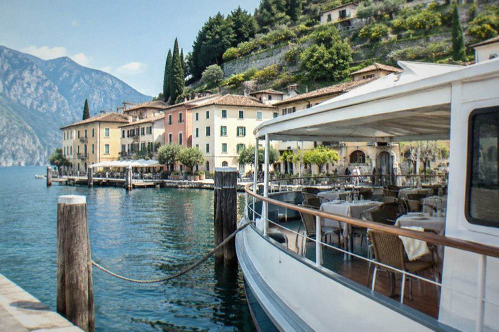 A cruise boat moored at a lakeside town with tables set for lunch on deck