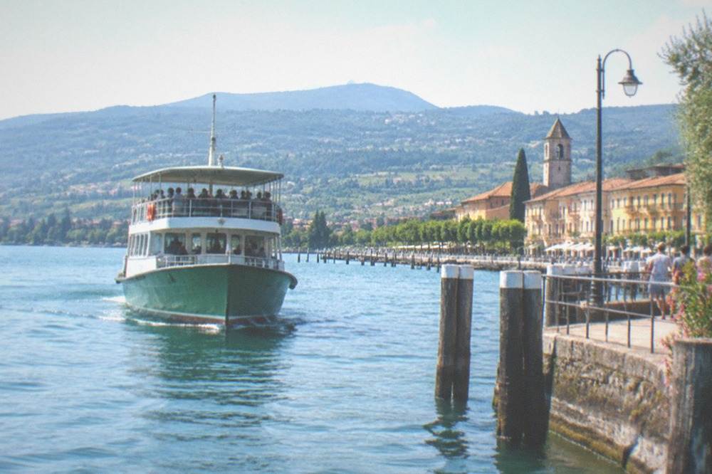 A public ferry with passengers on deck approaching a stone landing stage