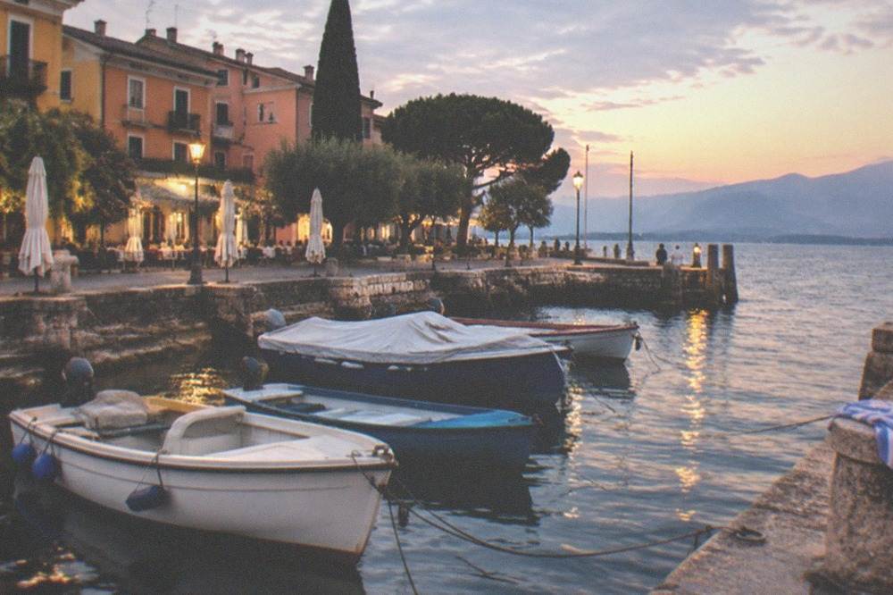 An evening harbour on Lake Garda with warm light on moored boats and a lakeside promenade