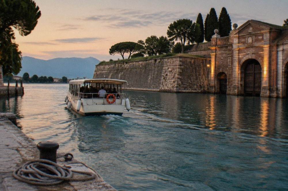 A passenger boat pulling away from a stone landing stage on the southern shore of Lake Garda