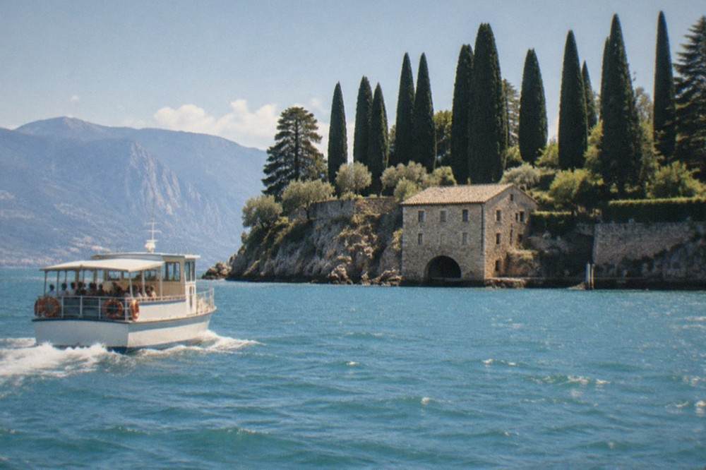 Sunny lake shore with a tour boat passing a stone castle on a warm afternoon