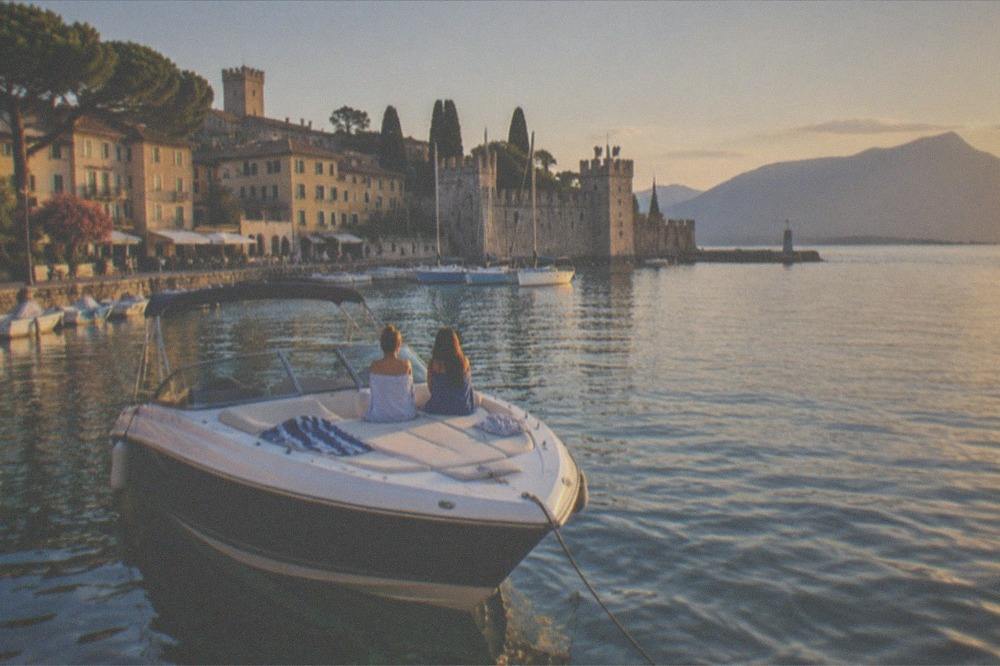 A private boat at anchor in a clear Lake Garda bay in late afternoon light