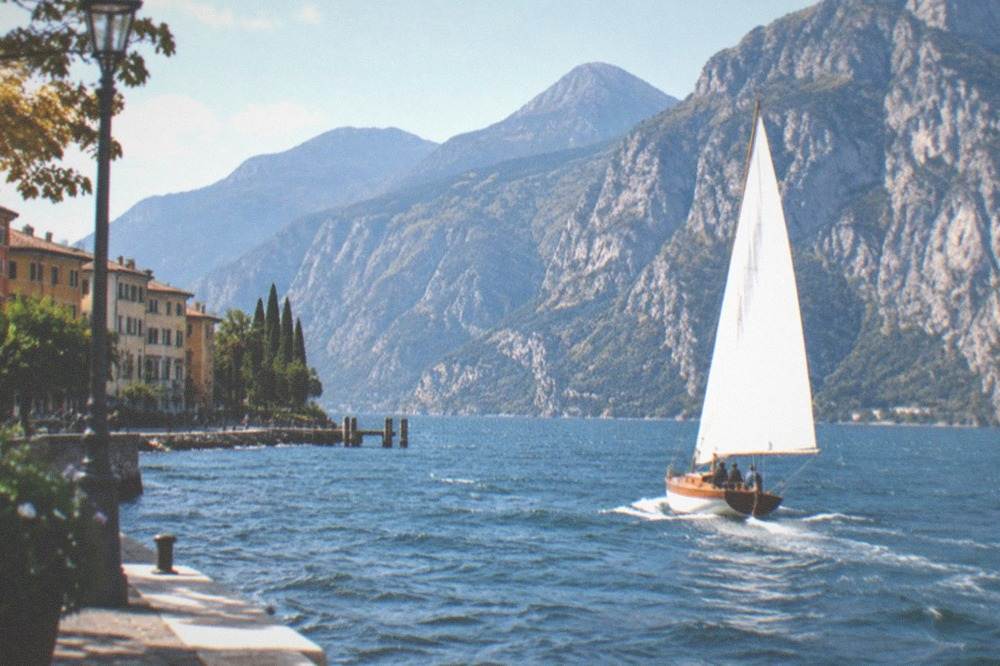 Historic wooden sailboat under way on open water with mountain ridges behind